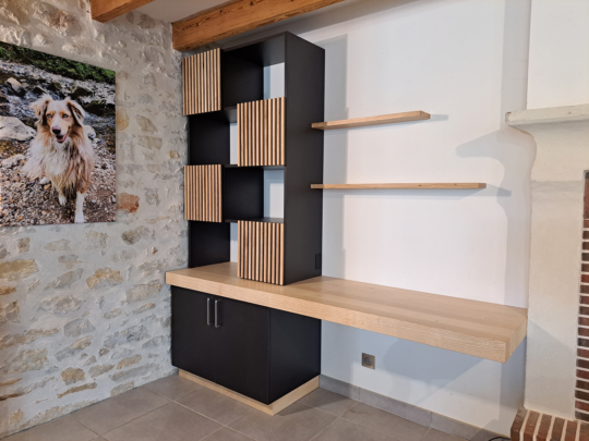 Ce bureau est en frêne massif et panneaux mélaminé noir mat soft black, les portes sont avec effet claustra, le plateau du bureau est suspendu, il y a deux étagères fixées au mur.