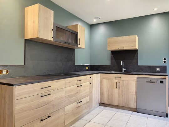 cuisine moderne en chene halifax et plans de travail et credence noir, avec ilot central table et espace colonne four